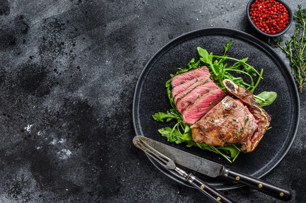 Medium rare sliced grilled striploin beef steak or new york steak. Black background