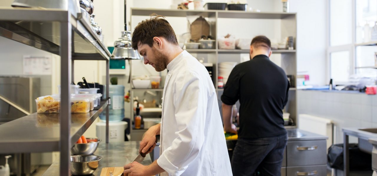 chef and cook cooking food at restaurant kitchen